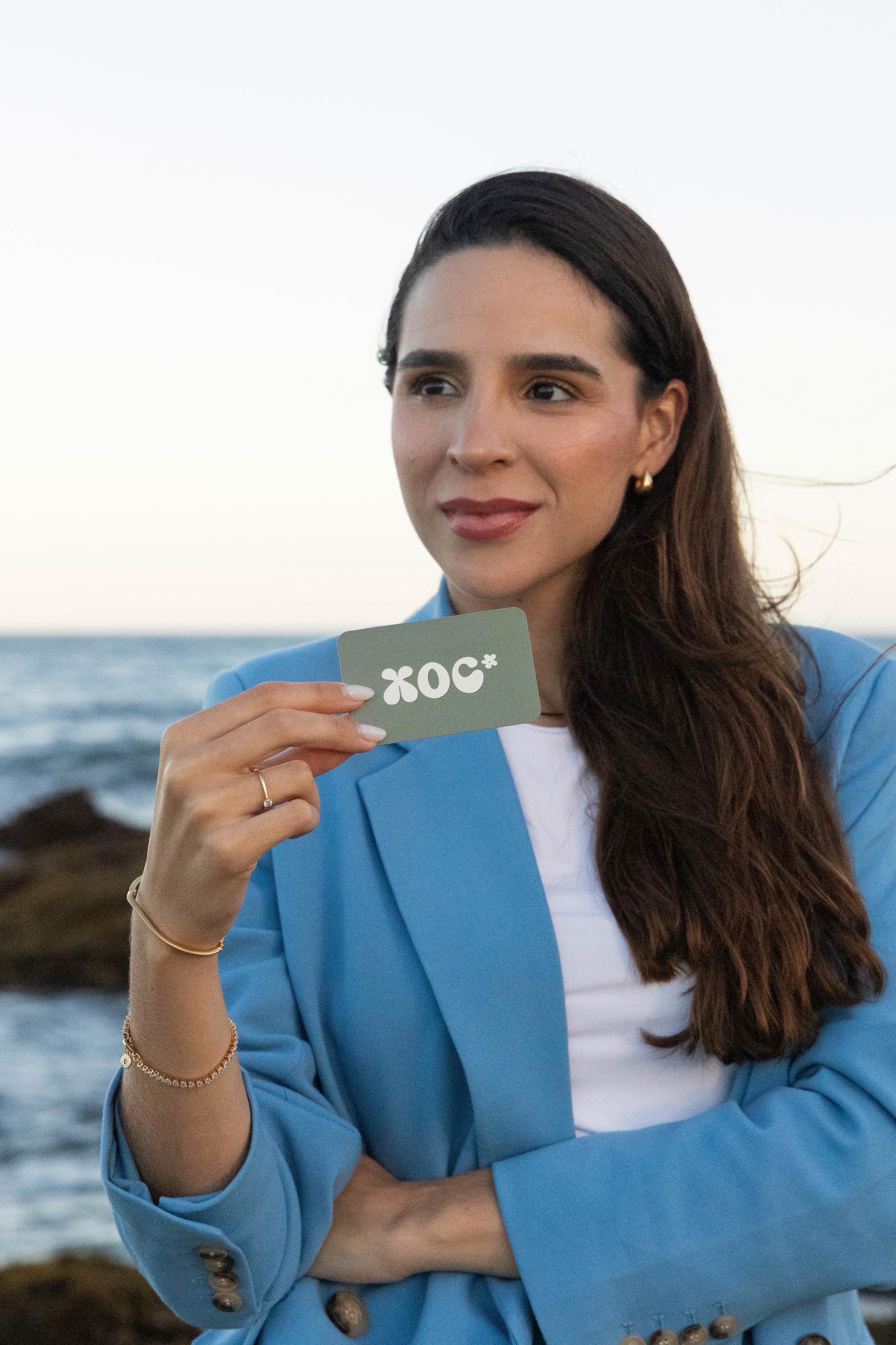 Fundadora do XOC Studio com cartão de visita junto à costa